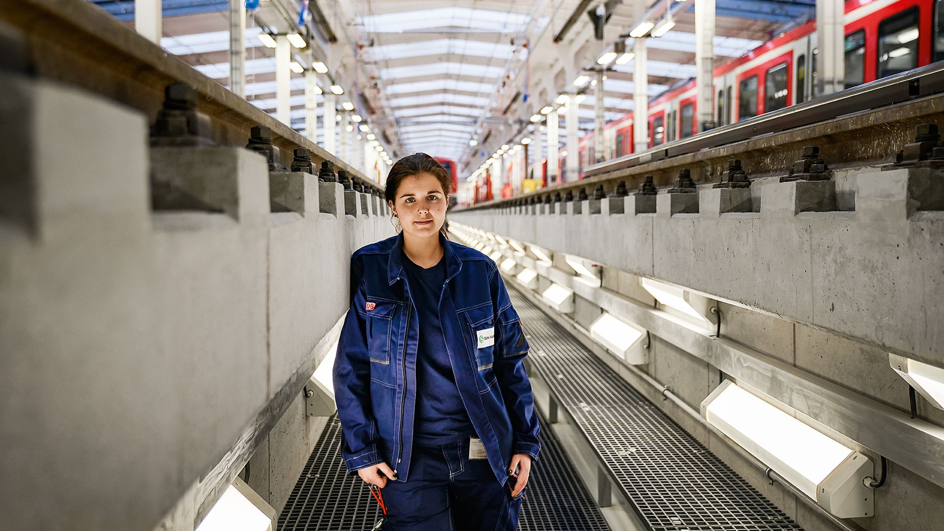 Eine Elektronikerin in Arbeitskleidung steht im Bahnbetriebswerk in der Wartungsgrube